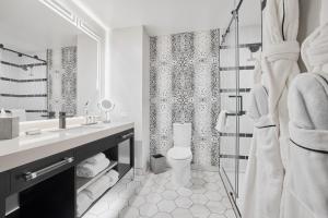 a white bathroom with a toilet and a shower at The Godfrey Detroit, Curio Collection By Hilton in Detroit +35 photos