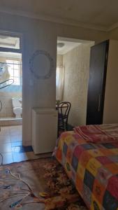 a bedroom with a bed and a bathroom with a sink at Millys Guesthouse Jhb in Johannesburg