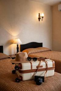 a suitcase with a hat and sunglasses on a bed at Meson de la Merced in Zacatecas +17 photos