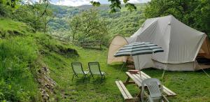 a tent with two chairs and a table and a bench at Ferme équestre de la Molière in Naves