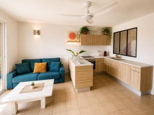 a living room with a blue couch and a kitchen at Between Caribean Seas in Cul de Sac