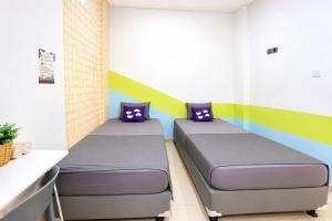 two beds in a room with colorful walls at Monggo Mampir Tanjung Duren By Reccoma in Jakarta