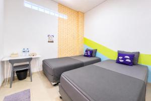 two beds in a room with a table and a desk at Monggo Mampir Tanjung Duren By Reccoma in Jakarta