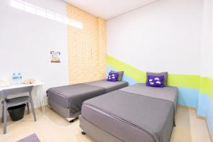two beds in a room with a desk and a table at Monggo Mampir Tanjung Duren By Reccoma in Jakarta