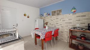 a kitchen with a table with red chairs and a refrigerator at Chalés Canto da Graúna in Ibicoara