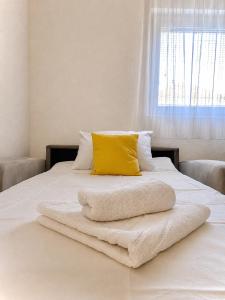 a bed with a yellow pillow and towels on it at Викендица Братунац in Bratunac