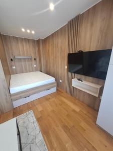 a small bedroom with a bed and a flat screen tv at Zlatibor 1 Balkan Square in Zlatibor
