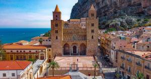 a large building in front of a city with the ocean at Nel Corso del Sogni Sicily Center Rooms in Campofelice di Roccella