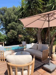 a patio with chairs and an umbrella next to a pool at Villa San Michele 3 chambres in Linguizzetta