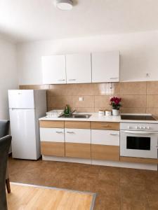 a kitchen with white cabinets and a white refrigerator at Викендица Братунац in Bratunac +6 photos