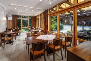 a restaurant with wooden tables and chairs and windows at Flair-Waldhotel Mellestollen in Saalfeld