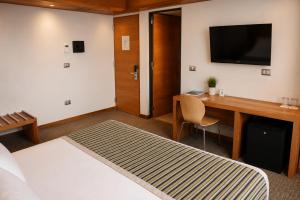 a hotel room with a bed and a desk with a television at Alto del Sol Costanera Antofagasta in Antofagasta