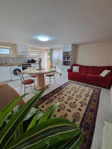 a living room with a red couch and a table at Le Jardin de Courcelle in Gif-sur-Yvette