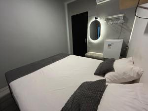 a bedroom with a bed with white sheets and a mirror at Suite Brisa da Colina in Garanhuns