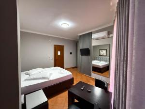 ein Schlafzimmer mit einem Bett, einem Tisch und einem Spiegel in der Unterkunft Hotel Kresko in Lushnjë + 39 Fotos