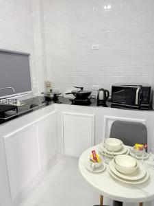 a white kitchen with a table with plates on it at Hana residence Bangtao BeachBangtao 11 Phuket in Ban Thalat Choeng Thale