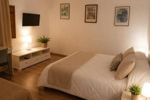 a bedroom with a white bed and a television at EL CHORRO Aire acondicionado Bar privado Barbacoa Amplios patios in Castalla