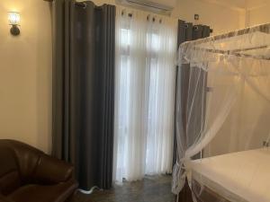 a bedroom with a window with curtains and a chair at Elysian Riverside in Weligama