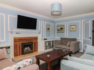 a living room with a fireplace and a flat screen tv at The White House in Okehampton