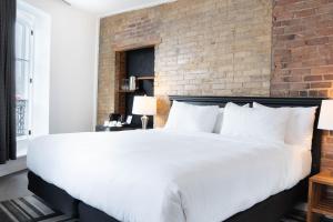 a large white bed in a room with a brick wall at Hotel Le Saint-Paul in Quebec City