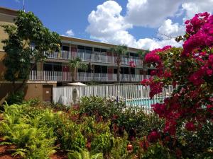 ein Apartmenthaus mit einem Blumengarten in der Unterkunft Red Carpet Inn Airport Fort Lauderdale in Fort Lauderdale