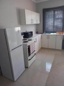 a kitchen with white appliances and white cabinets at Ocean Wave Chalets Unit 1 in Hibberdene