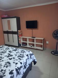 a bedroom with a bed and a flat screen tv at Ocean Wave Chalets Unit 1 in Hibberdene