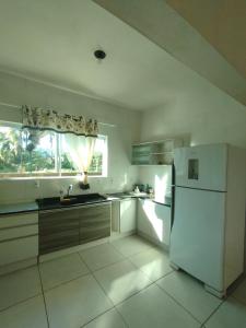 a white kitchen with a refrigerator and a window at O melhor de Garopaba in Garopaba