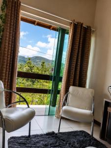 a living room with two chairs and a large window at O melhor de Garopaba in Garopaba