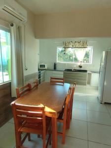 a kitchen with a wooden table with chairs and a refrigerator at O melhor de Garopaba in Garopaba +7 photos
