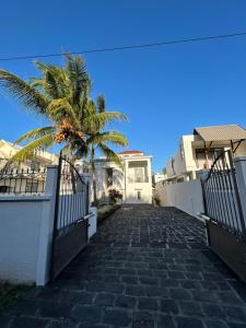 a cobblestone pathway leading to a house with a palm tree at Alizé Mont Choisy in Mont Choisy