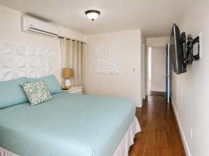 a bedroom with a blue bed and a television at Solea by The Sea in Roatán