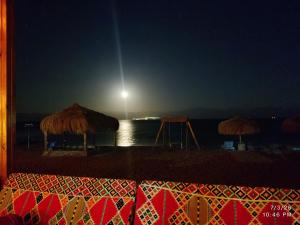 a beach with umbrellas and the ocean at night at Mermaid camp in Nuweiba