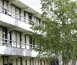 um edifício de apartamentos com varandas e uma árvore em Premiere Classe Niort Est La Creche em La Creche