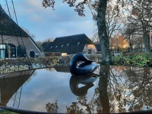 a black swan statue sitting on top of a pond at vakantiehuis in drenthe de hooizolder sauna bij te boeken in Gees