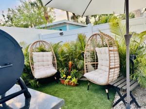two wicker chairs sitting on the grass with an umbrella at Walk to Siesta Key Beach-Remote Worker Friendly -High Speed WiFi- Bikes Included -Private Fenced In -Close to Restaurants, Coffee Houses & Shops - Paisleys Keep it Simple Casita in Siesta Key