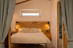 a bedroom with a bed with a wooden headboard and a window at Raíces da Costa Ártabra in Islote Mouron
