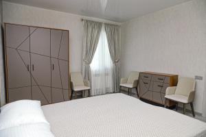 a bedroom with a bed and two chairs and a dresser at EVORI Guesthouse in Dilijan