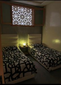 two beds in a room with a window at Appartement agadir centre in Agadir +44 photos