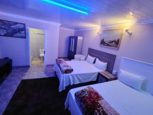 a hotel room with two beds and a bathroom at Wampex Guest House in Rustenburg