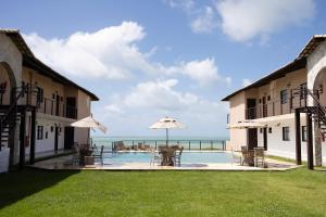 a pool with tables and umbrellas next to a building at Coleção Falésias de Pipa- by Arcbio Experience in Pipa
