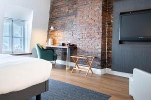 a bedroom with a brick wall and a bed and a desk at Hotel Le Saint-Paul in Quebec City +39 photos