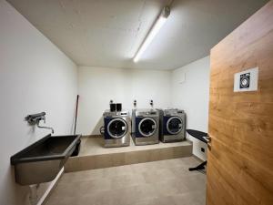 a laundry room with three washing machines and a sink at apartments '43 in Reith im Alpbachtal