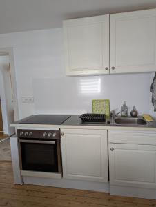 a kitchen with white cabinets and a stove and a sink at Familienhaus in Niedenstein +15 photos