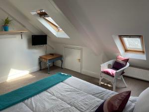 a attic bedroom with a bed and a chair at Penzance Central 1 & 2 Bedroom flats in Penzance