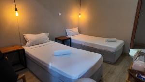 two beds in a small room with two tables and two at The Quiet Corner Guest House in Maputo