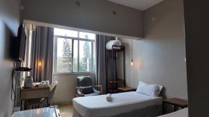 a room with a bed and a chair and a window at The Quiet Corner Guest House in Maputo