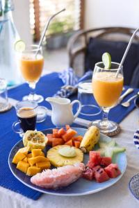a plate of fruit on a table with two glasses of juice at Parasol Doré - Boutique Hotel - in Dickwella