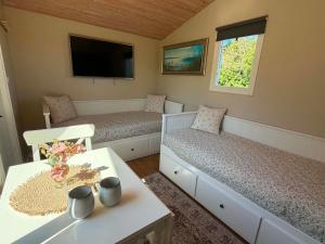 a room with two beds and a table and a tv at Stuga 1 Lillstugan in Ängelholm