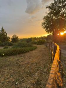 a fence next to a road with the sunset in the background at N1 Emplacement tente van camping-car in Saint-Aubin-de-Nabirat +10 photos
